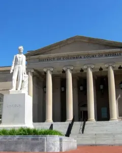 Abraham Lincoln marble statue on a stone pedestal in front of a classical courthouse building