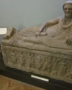 Sarcophagus of Laris Pulenas with a reclining male figure on the lid and carved relief figures along the base.
