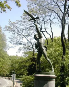 The Falconer bronze statue on a stone pedestal among trees in Central Park.