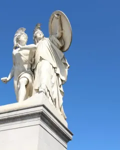 Athena Protects the Young Hero stone sculpture showing a helmeted goddess with shield and spear behind a young hero.