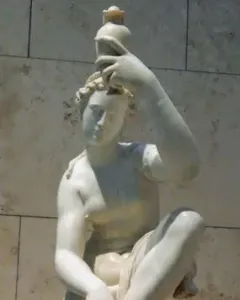 Seated marble female figure lifting one foot and holding a small vessel above her head.