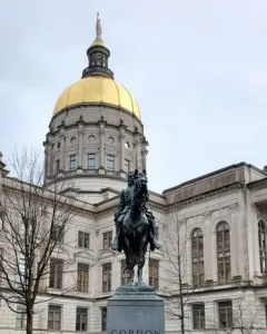 John Brown Gordon equestrian statue on a tall stone pedestal in front of a domed capitol building.