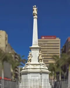 The Triumph of the Candelaria obelisk rises in an open plaza, with stone figures at the base and a white figure atop the monument.