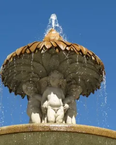 Fountain of the Artichoke with three cherubs supporting a leaf-covered stone canopy as water cascades over the edge.