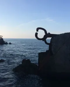 Peine del Viento sculptures silhouetted on rocky coastline beside a dark, choppy sea