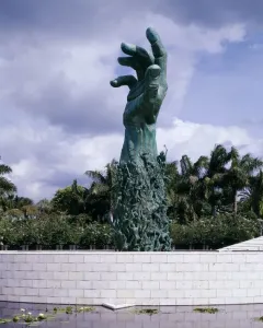 Holocaust Memorial sculpture in Miami Beach, a dark green raised arm and open hand rising above smaller figures and water.