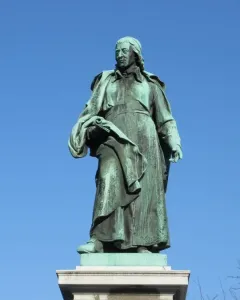 Vodnik Monument, a green-patinated statue of a man in historical clothing holding a rolled document on a white pedestal.