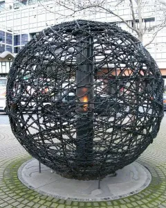 Universal Links on Human Rights sculpture with a dark spherical frame of chains and bars surrounding a central flame.