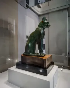 Gayer-Anderson Cat statue with a gold nose ring, earring, and decorated collar.