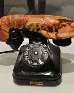 Salvador Dalí’s Lobster Telephone, showing a black rotary phone with a reddish-orange lobster on the cradle.