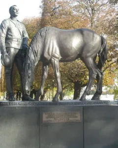 Monument to the Russian Expeditionary Force showing a uniformed man beside a horse with its head lowered, on a stone pedestal with Cyrillic and French inscriptions.