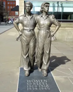 Women of Steel bronze sculpture of two women standing arm in arm in work clothes.
