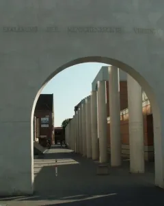 The Way of Human Rights concrete archway with engraved German text, framing a walkway lined with tall concrete pillars.