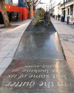 A Conversation with Oscar Wilde granite monument with a bronze bust holding a cigarette.