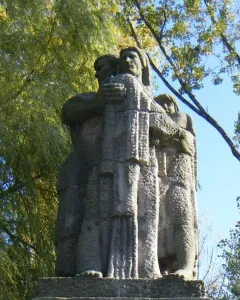 War Never Again stone monument showing a man embracing a woman and child on a tiered base inscribed “NIGDY WOJNY.”