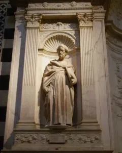 White marble statue of Saint Peter in the Piccolomini Altar at Siena Cathedral, shown in a twisting pose with a book held in his left arm.