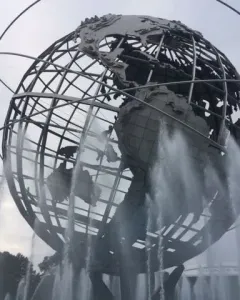 The Unisphere steel globe sculpture with orbital rings, surrounded by water fountains under an overcast sky.