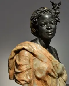 Bust of Woman from the French Colonies with dark textured hair, an ornate hair ornament, and a draped garment over her shoulders.