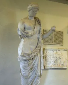 Damaged white marble statue of Armed Aphrodite with a bowed head and one arm missing.