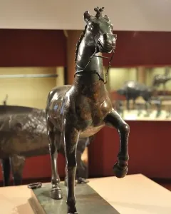 Bronze horse statue from the Neuvy-en-Sullias Hoard, shown with one front leg raised on a rectangular base.