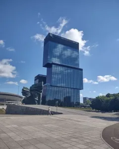 Silesian Insurgents\' Monument with three jagged dark forms on a stone base beside a glass skyscraper and domed building.