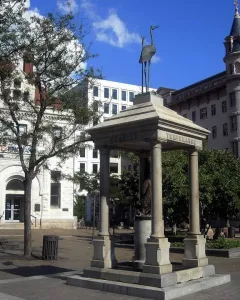 Temperance Fountain in a city square, with a stone pavilion and bird statue above it.