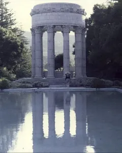 Pulgas Water Temple reflected in a still reflecting pool, with a lone person standing nearby.