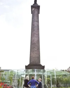 The Melville Monument rising above a green park with people walking along paved paths.