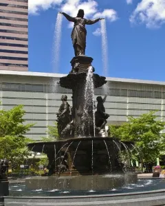 Tyler Davidson Fountain with a robed figure and smaller bronze figures in a city plaza