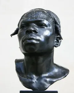 Dark metallic bust of an Aruwimi native with textured hair, a prominent nose, and an earring on a square base.