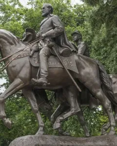 Robert E. Lee equestrian statue with a bearded rider on horseback, raising his hat, and a second mounted figure behind him.