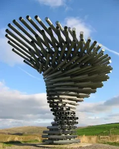 The Singing Ringing Tree sculpture made of grey metal pipes against a blue sky.