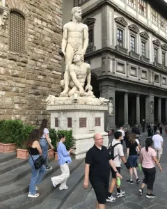 Hercules and Cacus sculpture on an ornate pedestal in Piazza della Signoria, showing two muscular figures in white marble.
