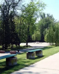 Table of Silence surrounded by hourglass-shaped chairs in a park setting.