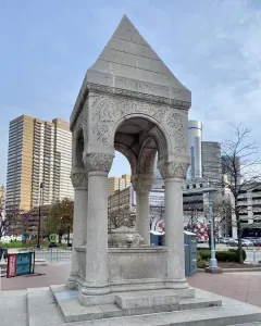 Bagley Memorial Fountain with a pyramidal roof, carved arches, and a lion-head relief in Detroit\'s Cadillac Square.