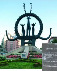 Hittite Sun Disk Monument with animal figures on a landscaped base in an urban setting.