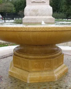 Butt–Millet Memorial Fountain with a shallow stone bowl, carved inscriptions, and an octagonal base in a pebbled basin.
