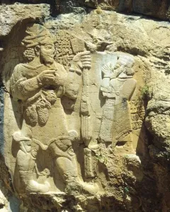 Ivriz relief showing two carved figures, one holding a staff and grapes.