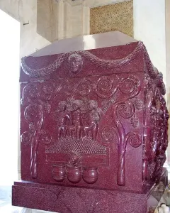 Sarcophagus of Constantina with carved grape-harvesting figures and vines on a red porphyry surface.