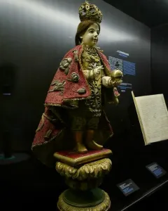 Santo Niño de Cebú statue with a golden crown, red embroidered cape, and golden orb with cross.
