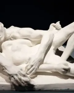 Auguste Rodin\'s Avarice and Lust showing two nude figures in a tight embrace on a base.