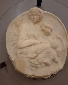Michelangelo’s Pitti Tondo relief sculpture showing the Madonna and Child with the young Saint John behind glass.