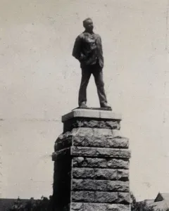 Statue of Cecil Rhodes standing on a tall stone pedestal.