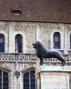 The Brunswick Lion statue stands on a stone pedestal in front of a historic stone building.