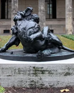 Bronze sculpture of Hercules wrestling the Nemean Lion on a stone pedestal.
