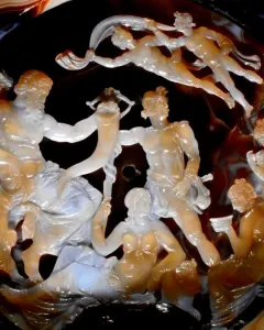 The Tazza Farnese carved gem shows a detailed relief scene with a bearded figure holding a horn among draped and partially nude figures.