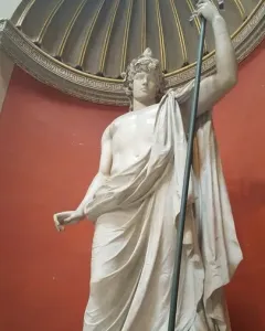 Antinous Braschi, a white marble statue of a youthful male figure with a bare torso, draped cloth, curly hair, and a raised staff.