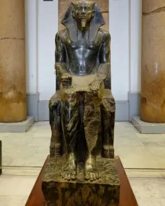 Khafre Enthroned, a dark stone statue of a seated pharaoh on an ornate throne with a falcon carved around the back.