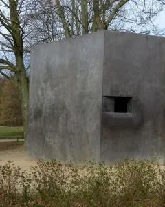 Memorial to Homosexuals Persecuted Under Nazism, a dark gray concrete block with a recessed opening in a park setting.