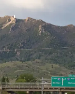 Our Lady of the Rockies statue standing on a rocky mountain peak with outstretched arms.